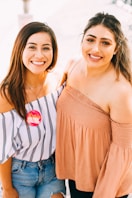 2 smiling women wearing brown knit tops
