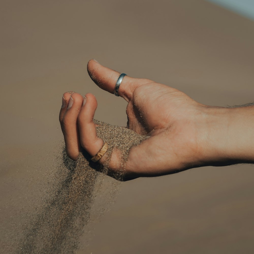 person wearing silver ring on brown sand