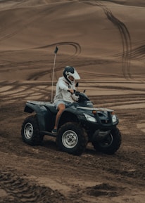 man in white helmet riding atv on brown sand