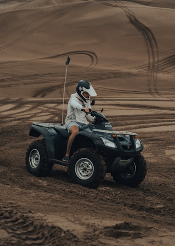 man in white helmet riding atv on brown sand