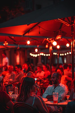 People sitting at outdoor tables enjoying a variety of street food dishes under string lights