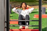 woman in white long sleeve shirt and black pants sitting on red metal frame