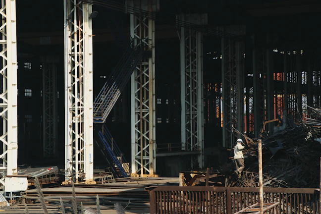 Workers carefully sorting piles of scrap metal in a bright warehouse.