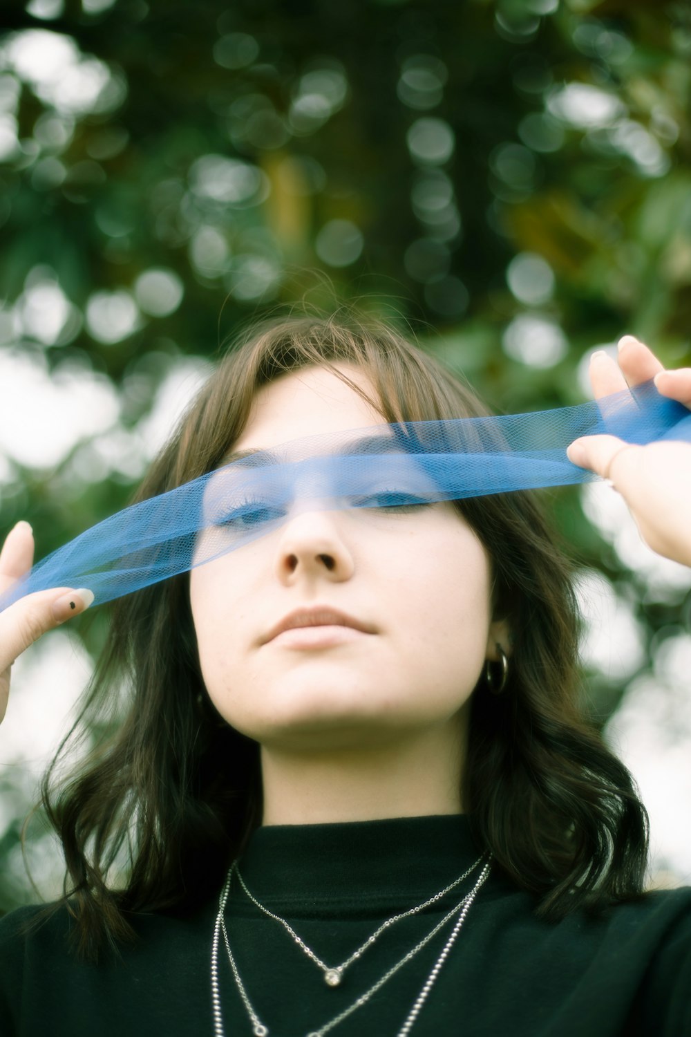 woman in black shirt holding blue scarf