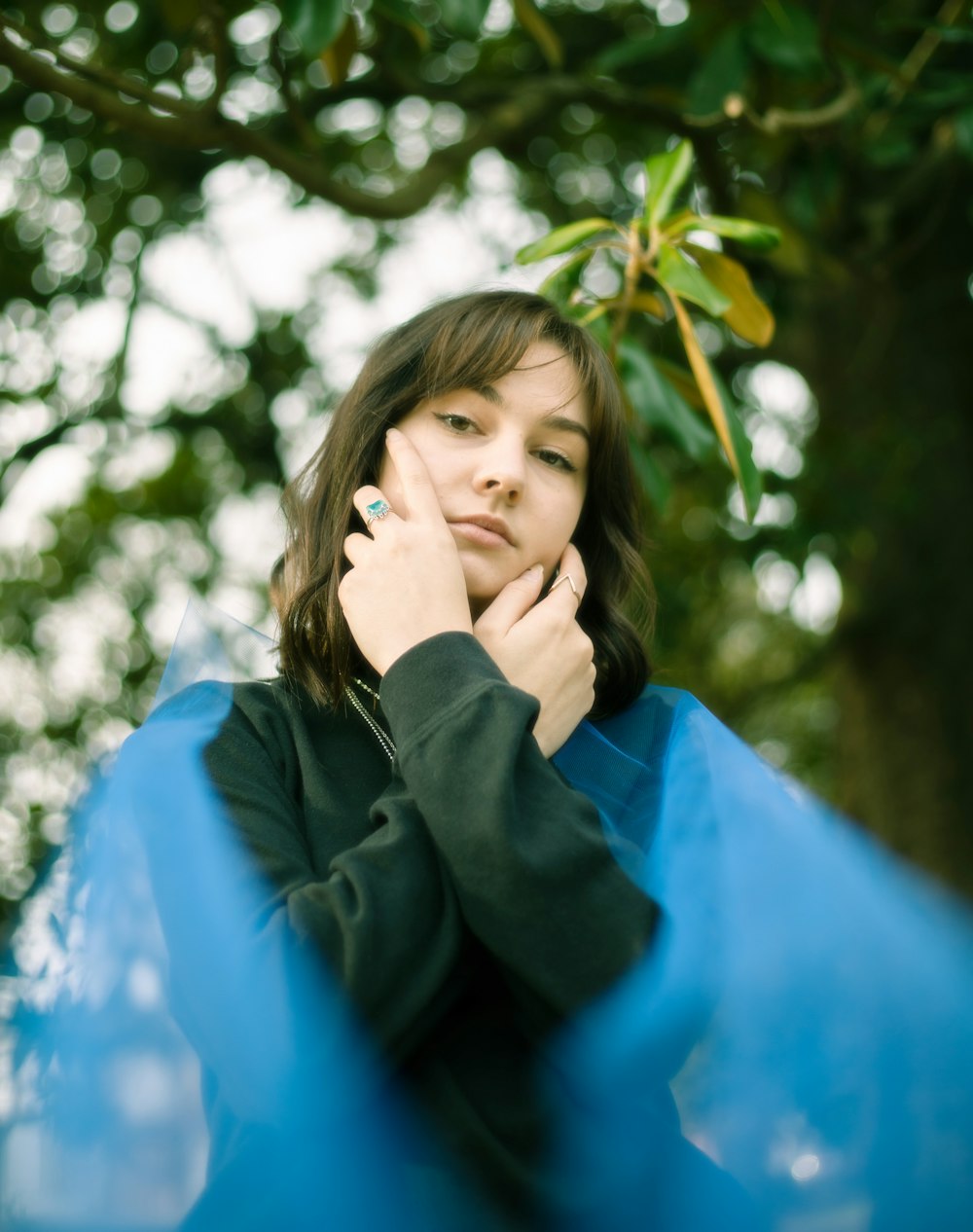 woman in black jacket standing under green tree during daytime