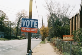 a vote sign on a pole next to a street