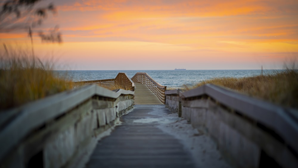 white wooden dock on sea during sunset