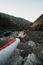A rugged explorer using a handheld GPS device against a twilight mountain backdrop.
