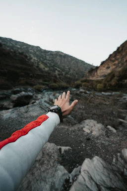 A rugged explorer using a handheld GPS device against a twilight mountain backdrop.