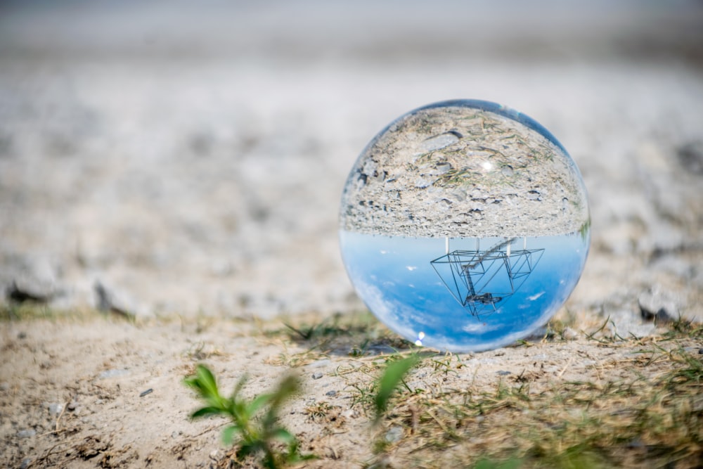 bola de vidro azul e branca na areia marrom