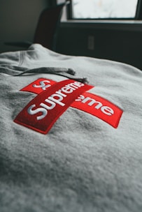 Una vista de primer plano de una sudadera gris con un logotipo rojo con texto blanco en cruz