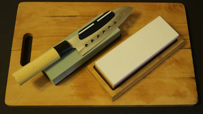 Close-up of a chef’s knife being expertly sharpened on a whetstone.