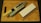 A kitchen knife with a beige handle rests on a sharpening stone, next to a whetstone on a wooden cutting board. The knife has multiple cutout holes in the blade.