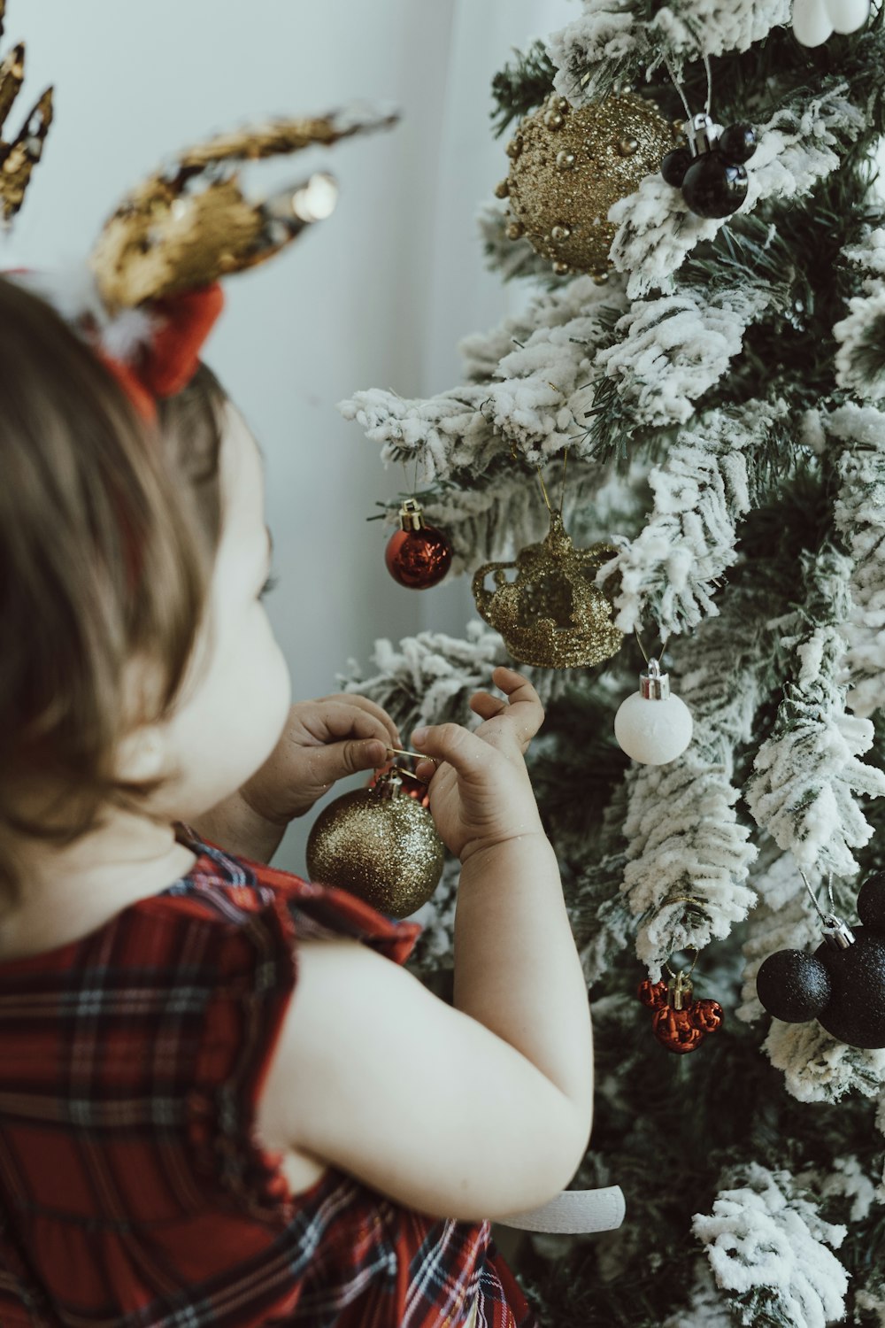 girl in red and white plaid dress holding gold and silver baubles