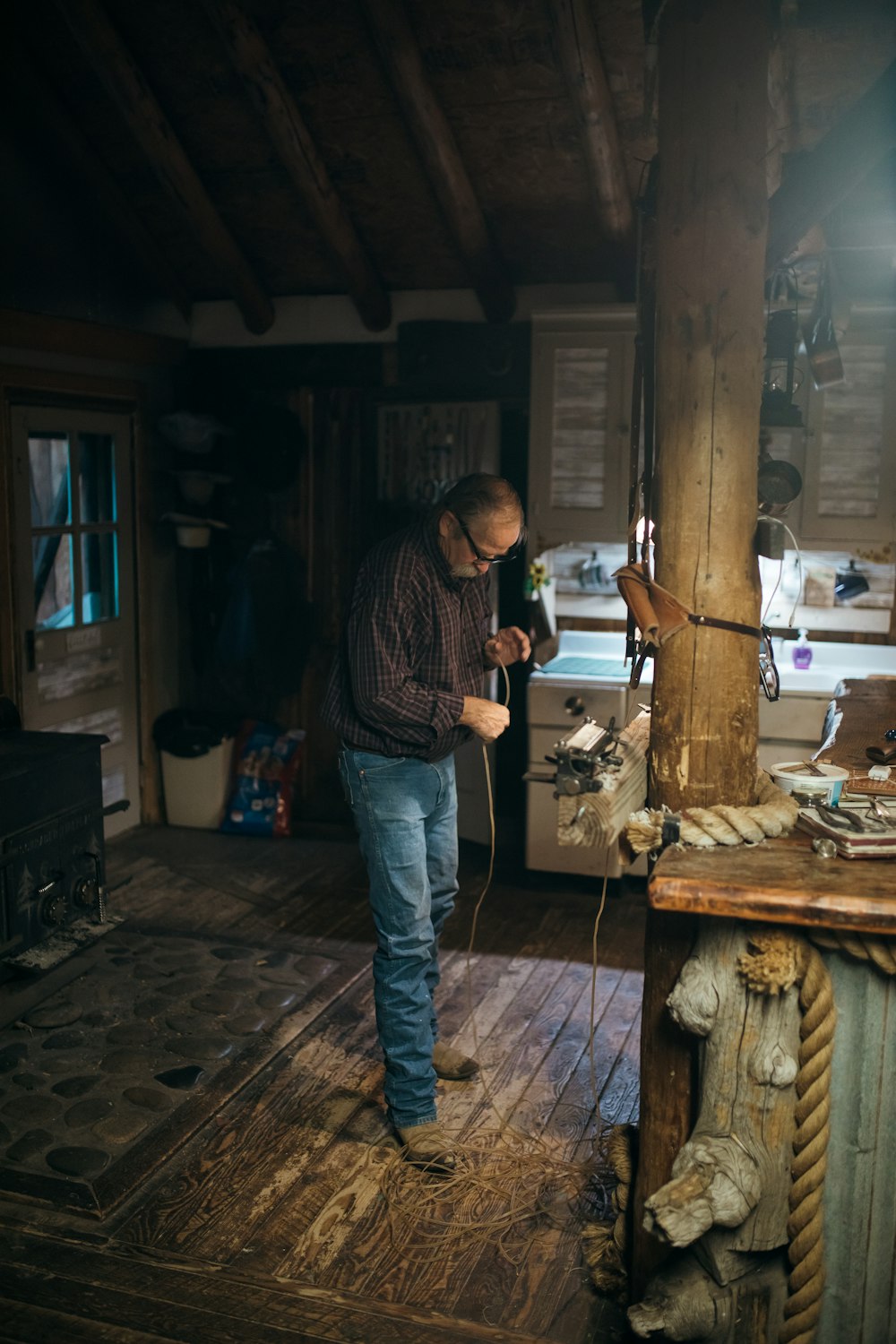 Mann in schwarz-weiß kariertem Hemd und blauer Jeans in der Nähe von braunem Holz