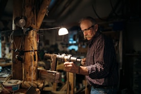 A carpenter shaping wood in a bright workshop