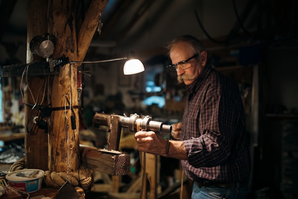 Artisan crafting eyeglass frames in a workshop with detailed tools.