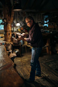 A craftsman carefully assembling a firewood sprinkler in a bright workshop.