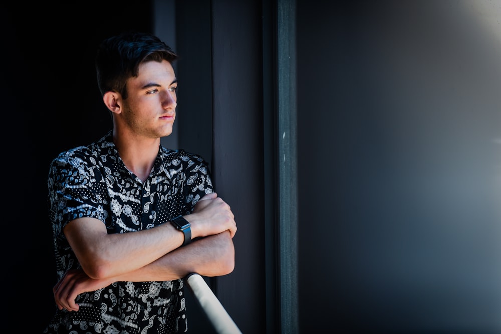 man in black and white floral button up shirt sitting by the window