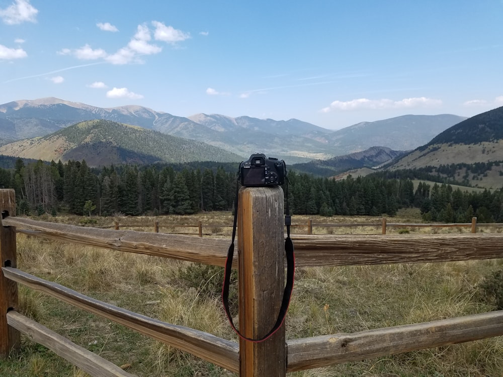 black and brown backpack on brown wooden fence