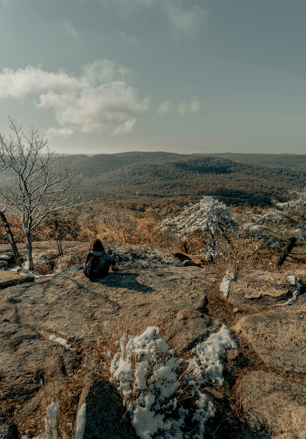 man in black jacket sitting on brown rock during daytime