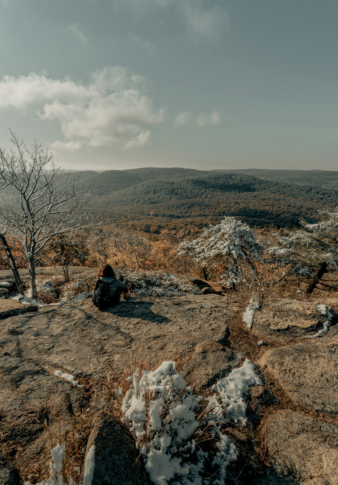 man in black jacket sitting on brown rock during daytime