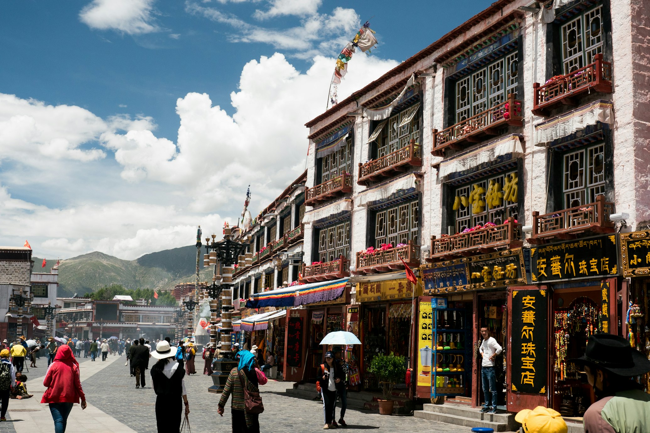 Delle persone camminano in una via del centro di Lhasa in Tibet