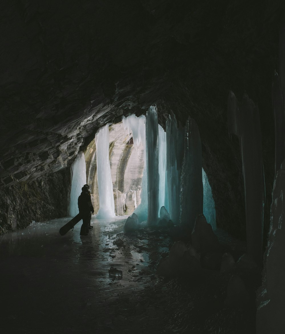 person in black jacket standing on ice cave