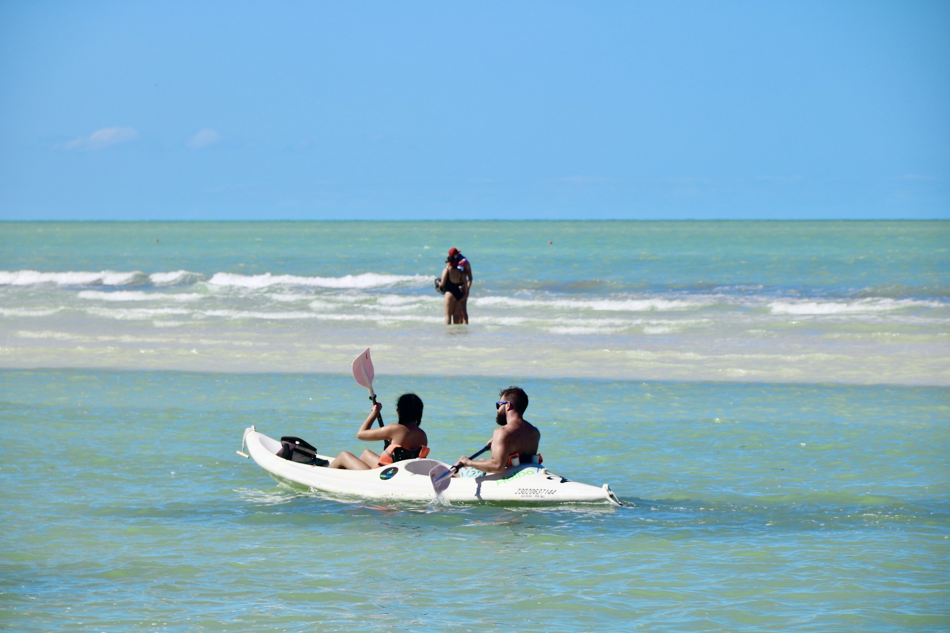 2 women sitting on white surfboard on beach during daytime