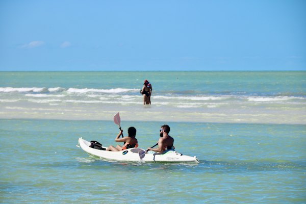 2 women sitting on white surfboard on beach during daytime — Isla Holbox, Mexico