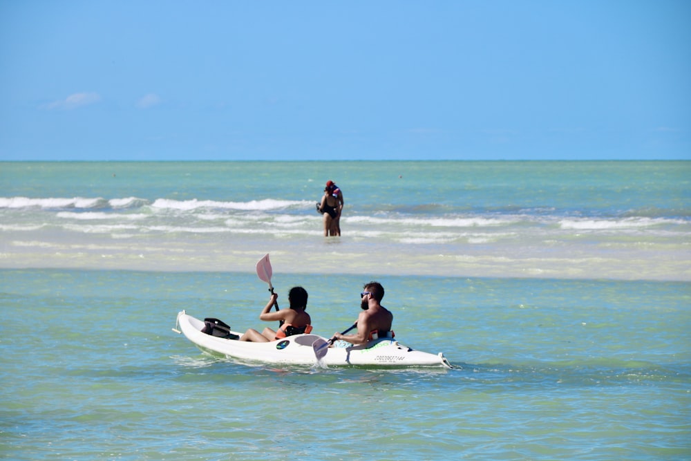 2 women sitting on white surfboard on beach during daytime