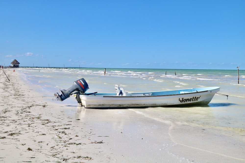 white and blue boat on beach during daytime