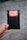 A hand is holding a small black bubble mailer against a blurred background. The mailer has a bright red and white label with the words 'HANDLE WITH CARE FRAGILE THANK YOU' printed on it.