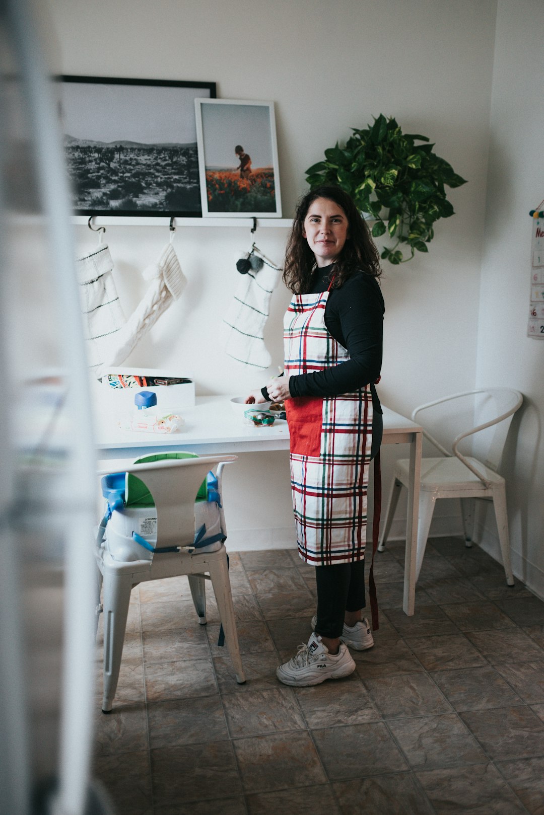 woman in black long sleeve shirt and red white plaid skirt standing near white table