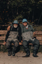 2 men sitting on brown wooden bench during daytime
