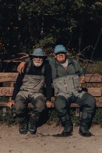 2 men sitting on brown wooden bench during daytime