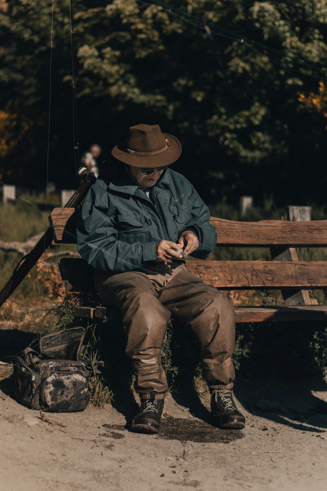 man in brown cowboy hat sitting on brown wooden bench