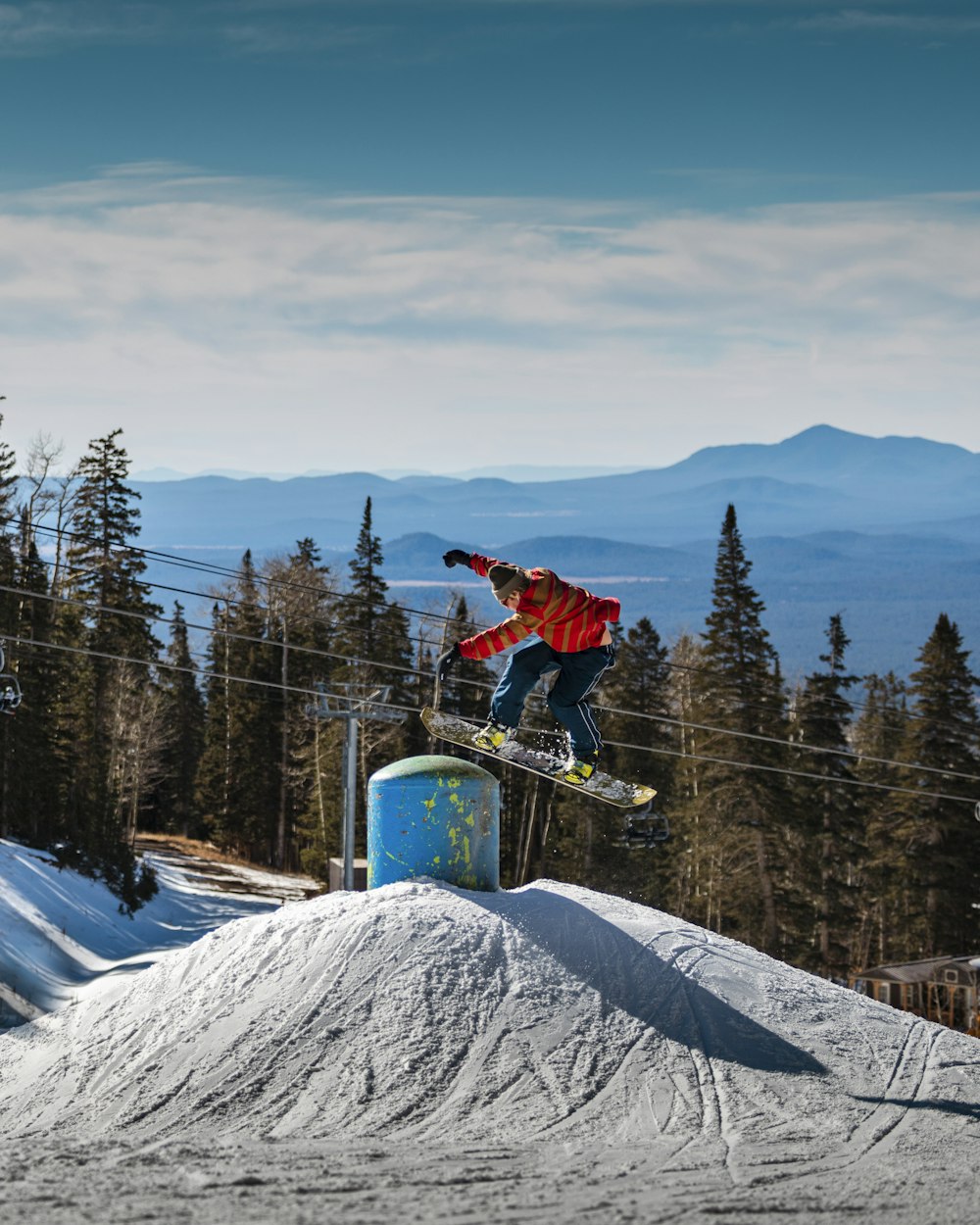 man in red jacket and blue pants riding on blue and yellow snowboard during daytime