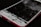 A smartphone with a severely cracked and shattered screen, exposing the inner components. The body of the phone is red, and the damage suggests impact or pressure.