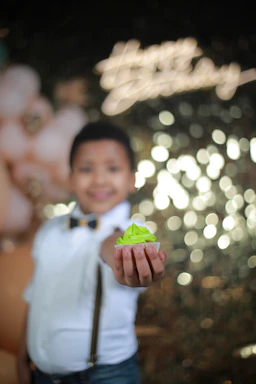 A cheerful child holding a colorful birthday cupcake with healthy ingredients around.
