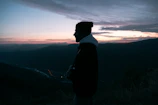 Model wearing a sandy beige hoodie with desert mountain silhouettes at sunset