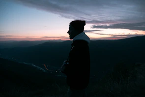 Model wearing a sandy beige hoodie with desert mountain silhouettes at sunset