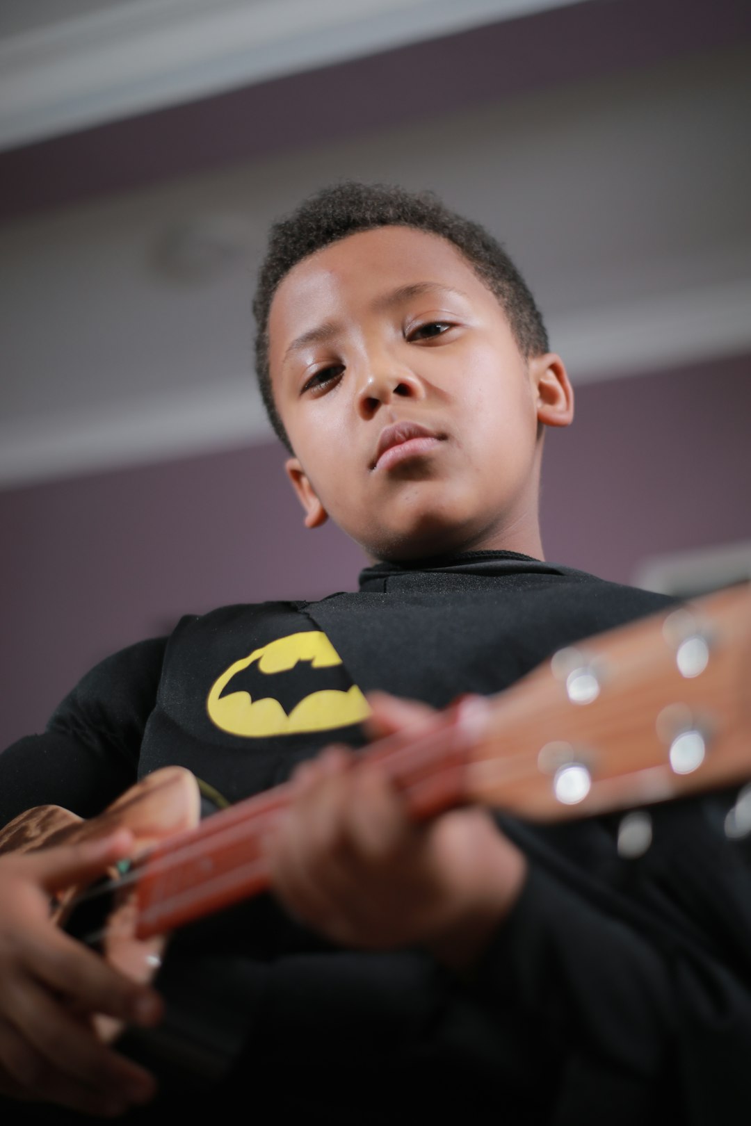 boy in black and yellow batman shirt playing guitar
