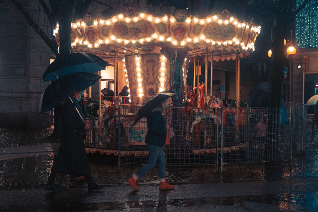 woman in black jacket holding umbrella walking on street during night time