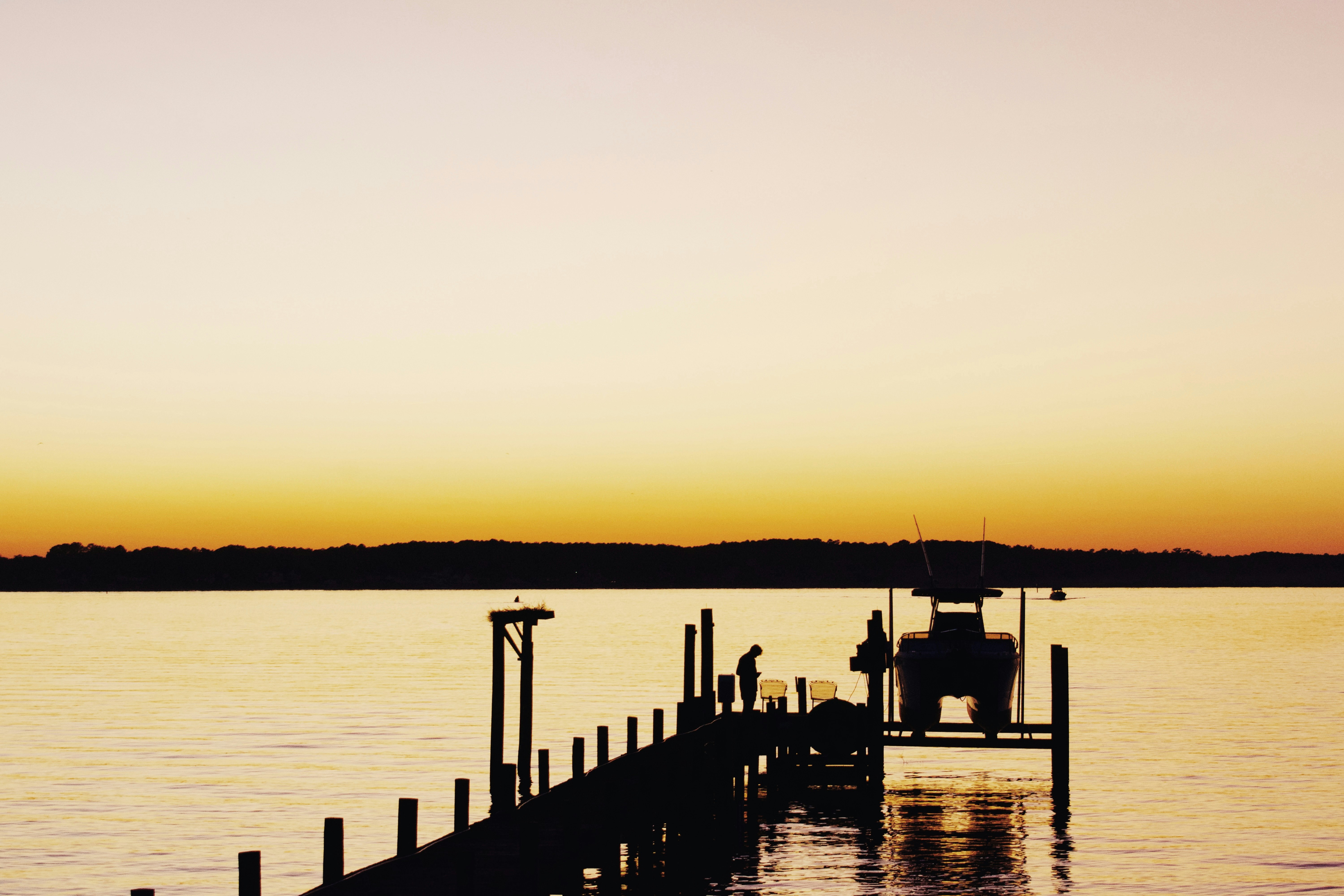 A sunset over the Potomac River with a dock and boat on the river in the foreground.