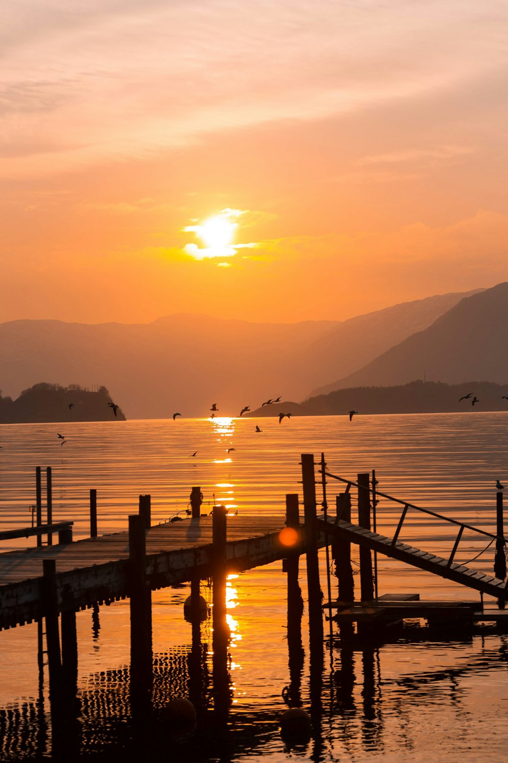 brown wooden dock on sea during sunset