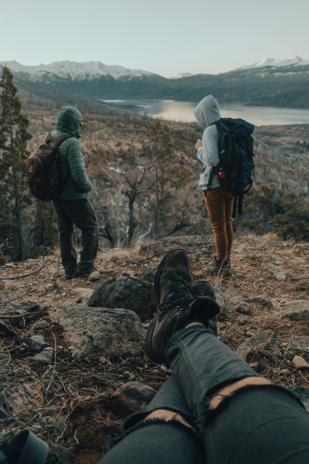 man in black jacket and brown pants with black hiking backpack standing on brown rock during