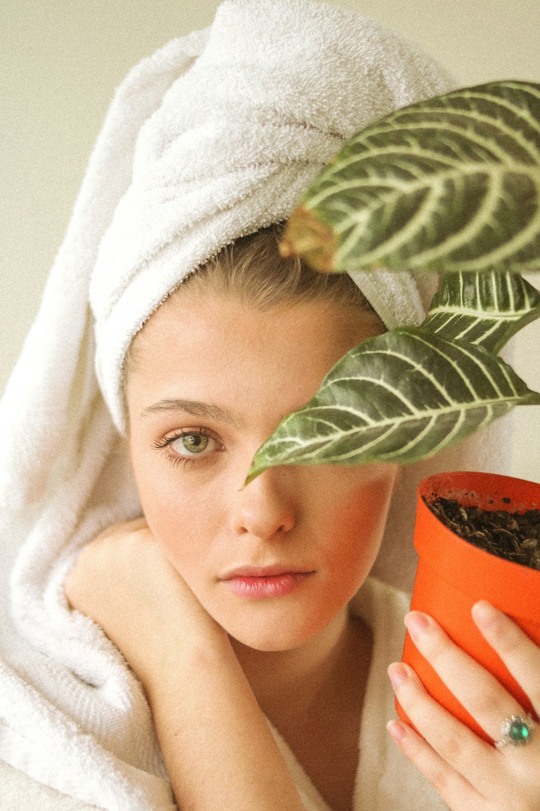 girl in white bath towel holding brown pot with green plant