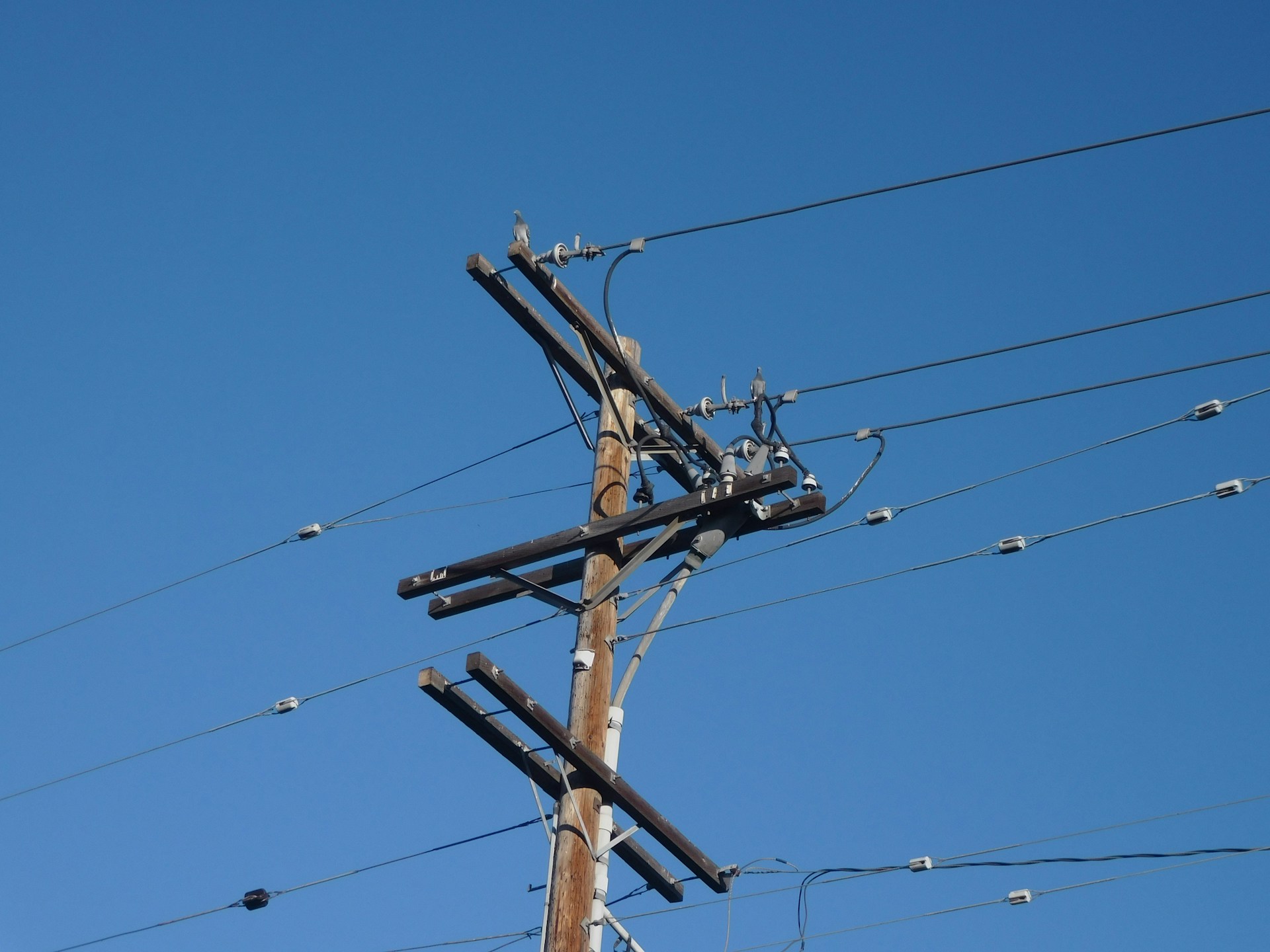 brown wooden electric post under blue sky during daytime