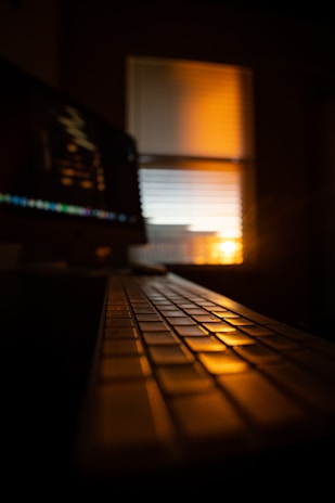 A serene photo of hands typing on a keyboard illuminated by warm morning light.